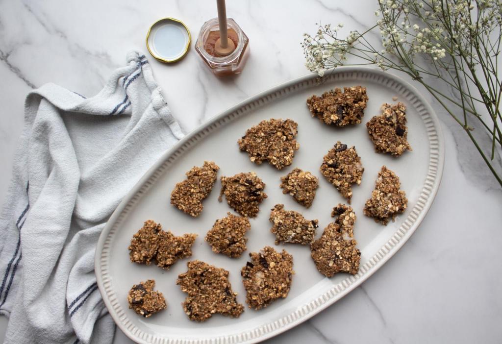 Granola bark recipe is plated on a serving platter next to a small jar of honey.