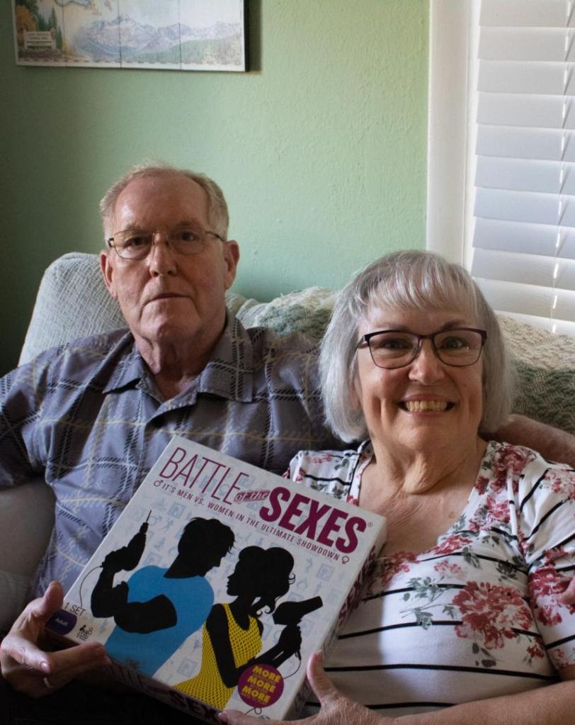 A man and woman hold up a board game.