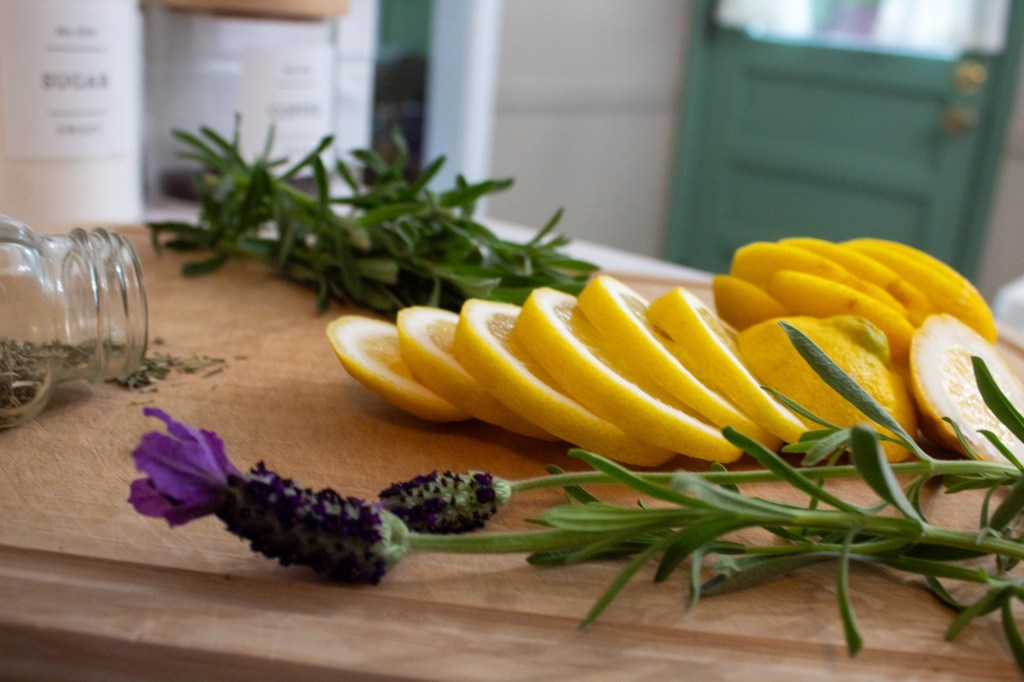 A simmer pot has spring ingredients prepared for it on a wooden cutting board.