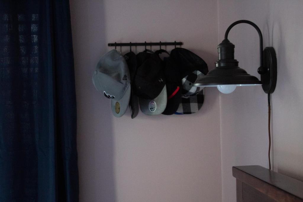 Hooks for hats are added to a corner of a pink cottagecore master bedroom.