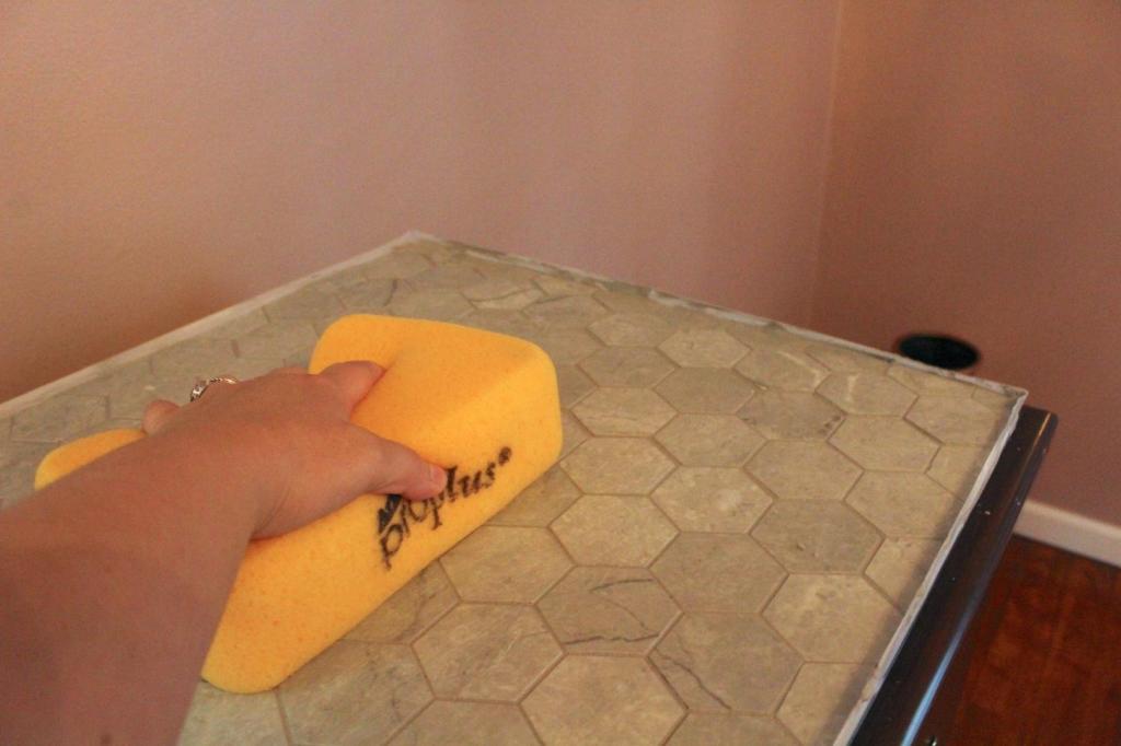 A sponge is used to clean off remaining grout from the tile surface.