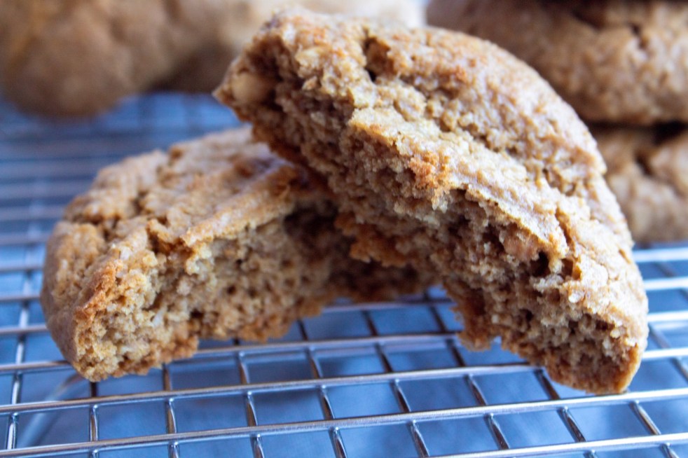 Thick, cake refined sugar free peanut butter cookies are cut in half and stacked on a cooling rack.