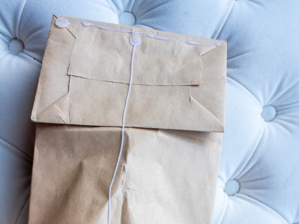 Paper sacks have a T shape drawn on them with hot glue for a paper snowflake tutorial.