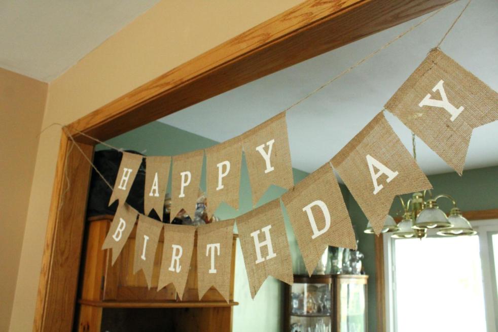 A Happy Birthday banner is hanging in an entryway as part of an 80th birthday idea.