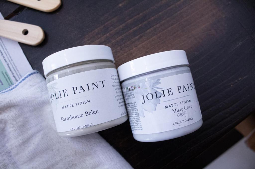 Two pastel stone colored paints lay on a wooden table.