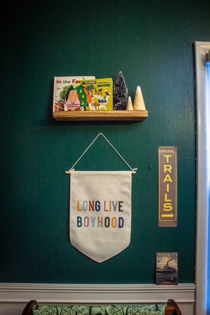 A wall has a banner, hiking sign, and outdoorsy books.