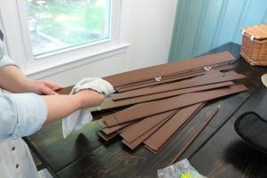 A woman is wiping down window blind slats.