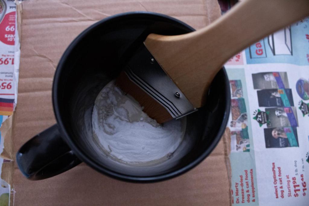 Baking soda is being mixed into paint in a black mug.