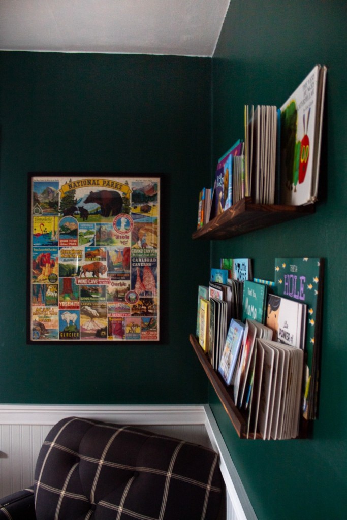 Books line shelves and juxtapose a framed national parks puzzle on the walls of a nursery.