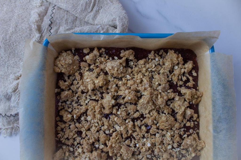 An oatmeal mixture has been sprinkled on top of the jam layer.
