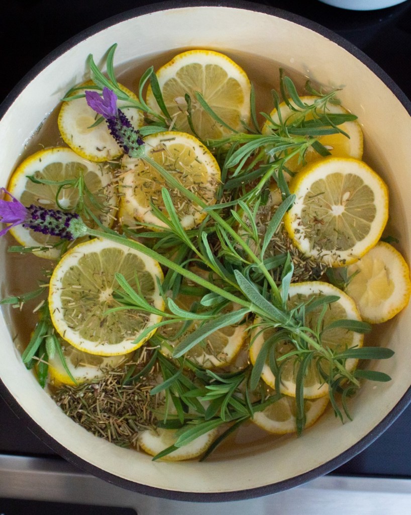 A simmer pot is created by adding flowers, herbs, and lemons into a pot of water on the stovetop.