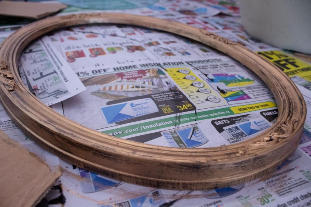A picture frame lays on newspaper after adding rub n buff to it.