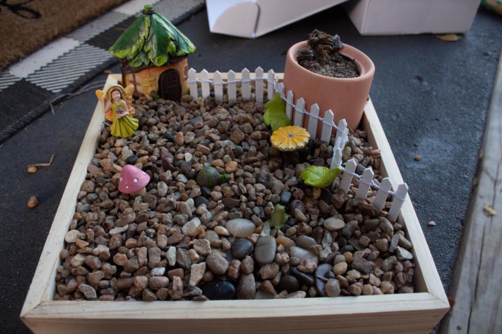 A DIY outdoor fairy garden is surrounded by solar=powered mushroom lights on an outdoor patio.