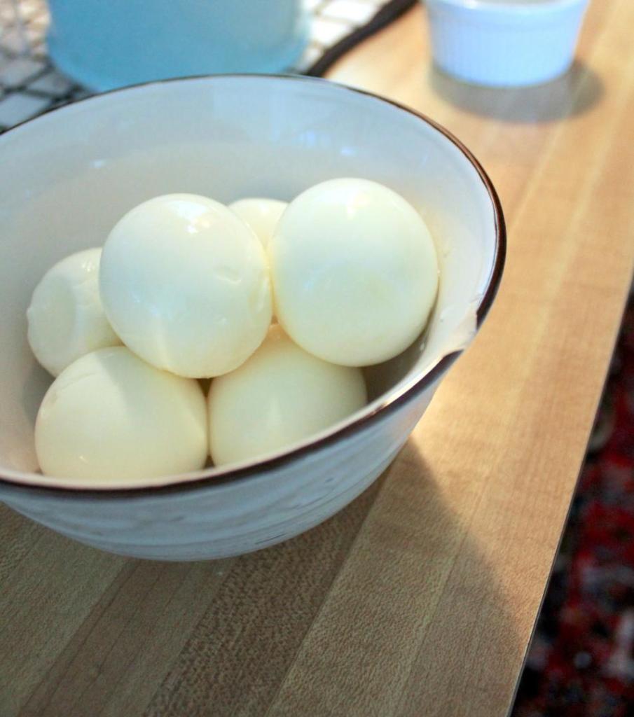 Hard-boiled eggs sit in a bowl on a countertop.