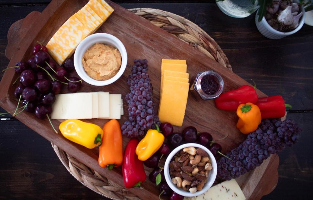 Veggies and fruits fill a wooden board.