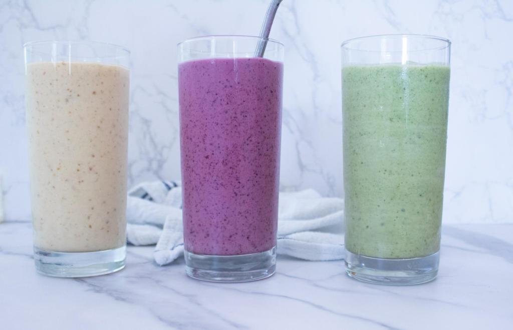 Easy, healthy smoothie recipes are made three different ways and lined up on a countertop in their bright colors.