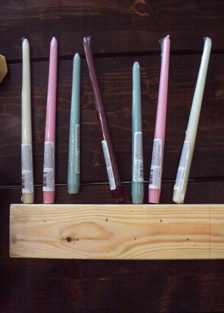 Dots are marked on wood for drilling holes. Candles indicate where these marks are made.