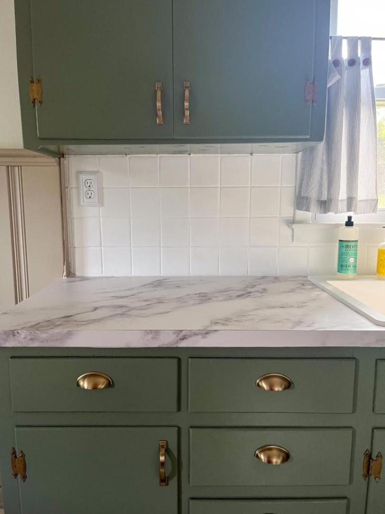 Kitchen cabinets are shown in a newly renovated cottage kitchen after learning  how to paint kitchen cabinets without sanding.