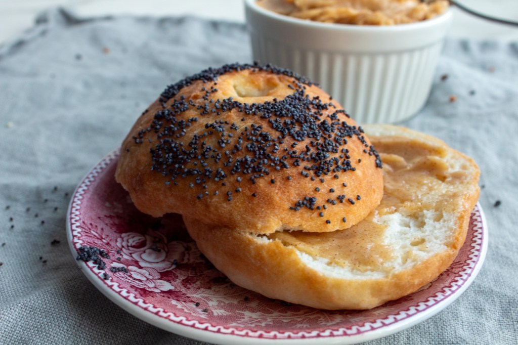 Cinnamon Honey Butter is slathered onto a bagel on a small dish.