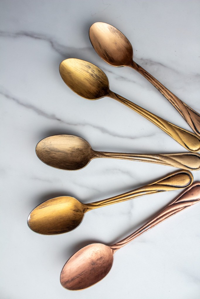Five gold rub n buff colors are shown painted onto spoons.
