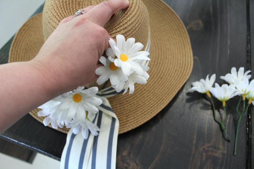 A woman sticks flowers under ribbon.