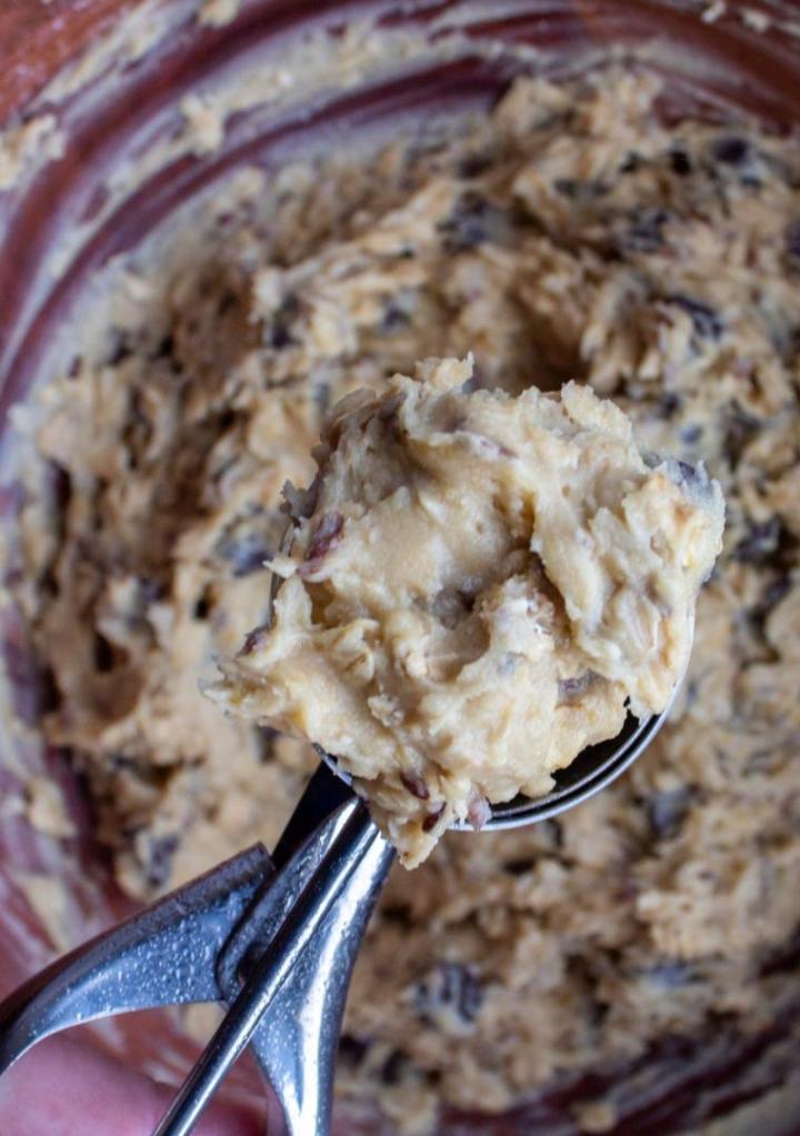 An easy lactation cookies recipe is shown with the dough in a bowl and a scoop full of cookie dough with chocolate chips.
