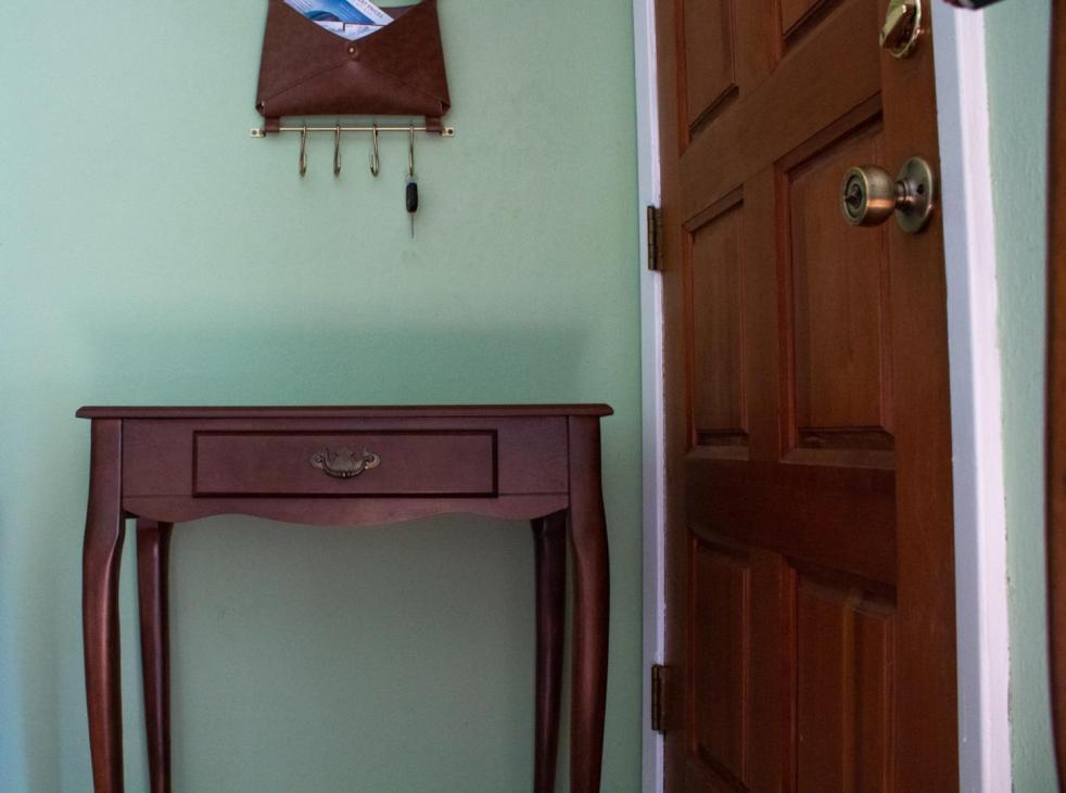 A make-up table is shown against a light green wall to show how to refinish wood furniture.