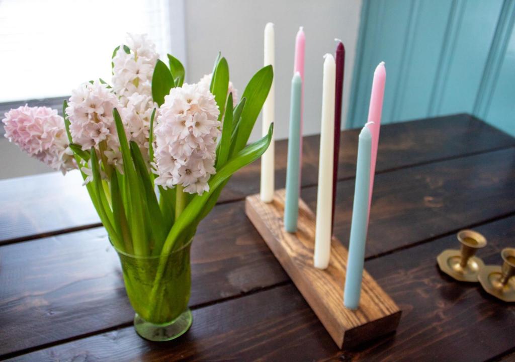 Candles are inserted into wood decor on a table next to flowers.