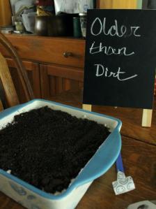 A dirt cake has a sign next to it that reads "Older than dirt."