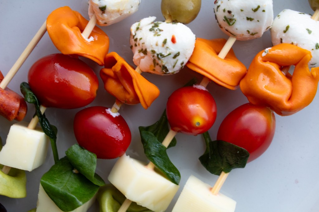 Italian ingredients are added to wooden skewers and laid side by side.