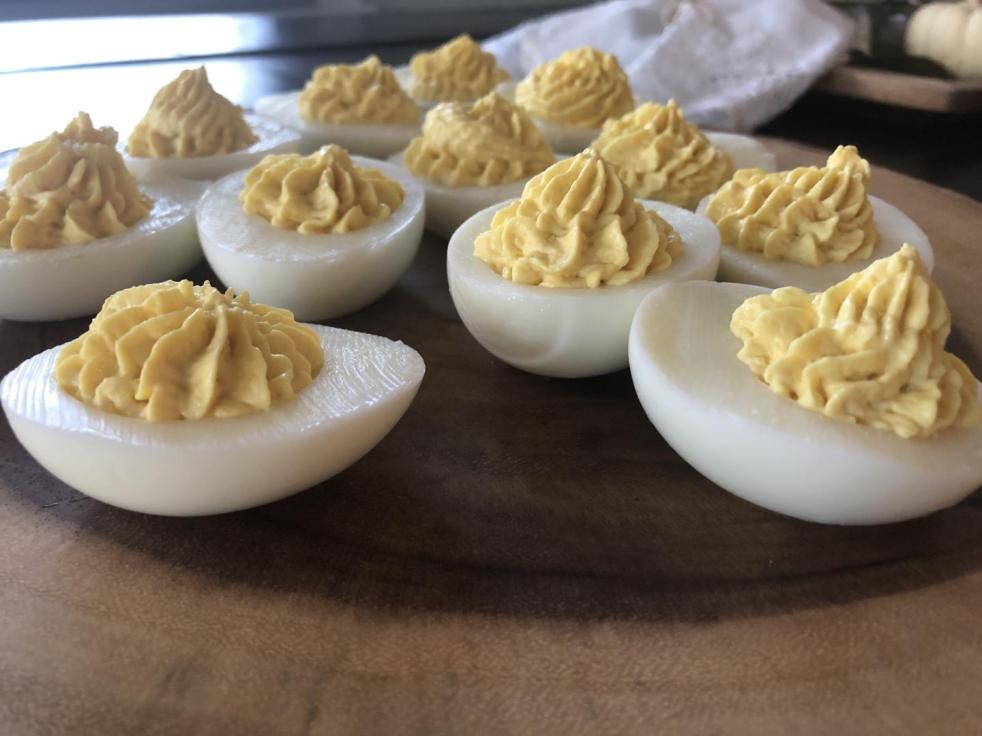 The best deviled egg recipe is set out on a wood serving board.
