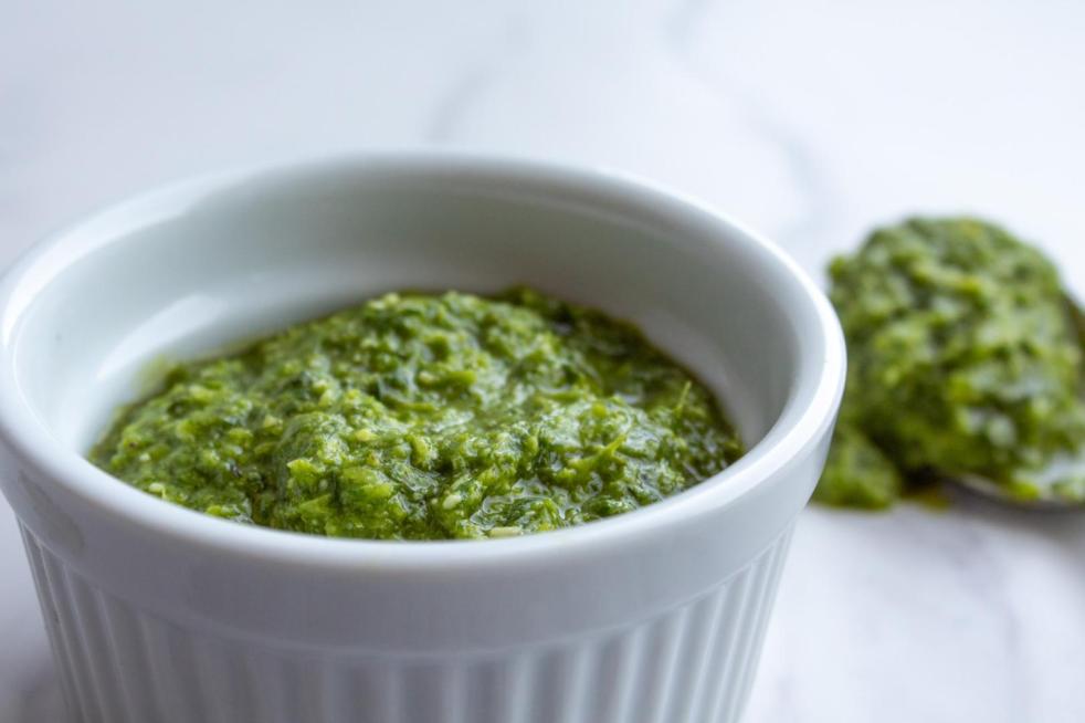 Garlic scape pesto is spooned out of a ramekin.