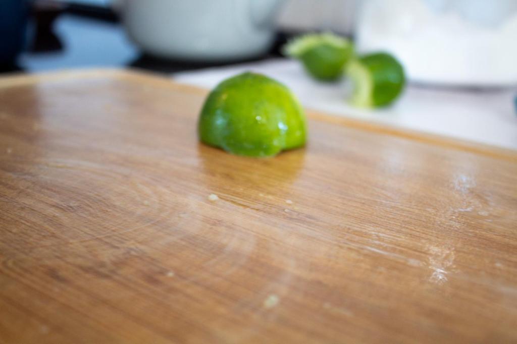 A woman is using a lime to clean a cutting board.