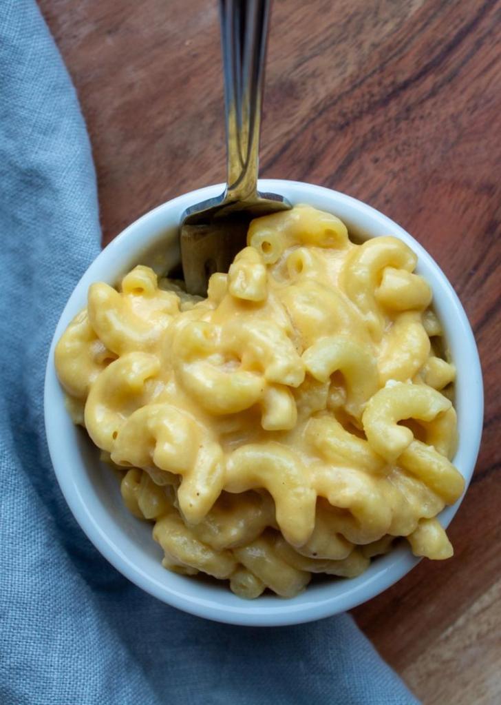 Homestyle Mac and cheese is shown in a ramekin with a fork in it.