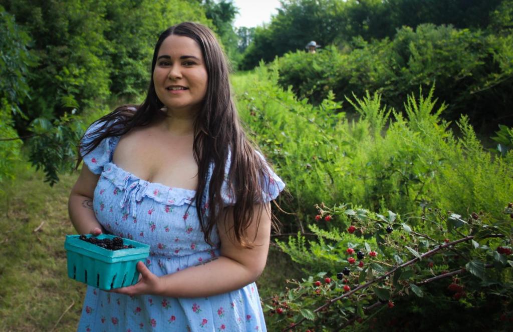 A woman picks berries in a patch.