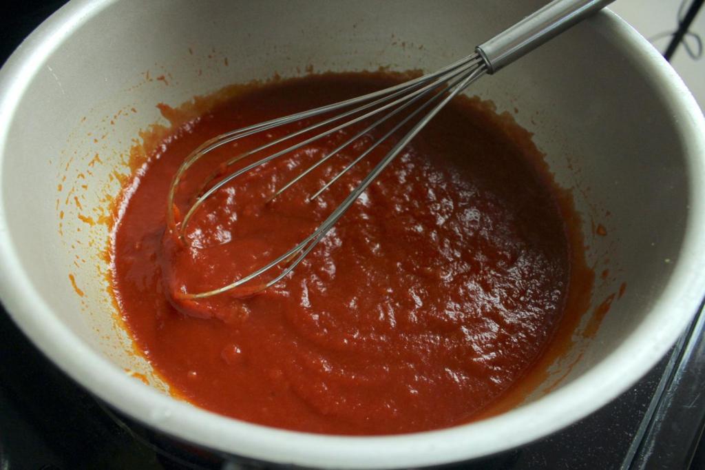 Tomato paste has been added to a pot of onions.