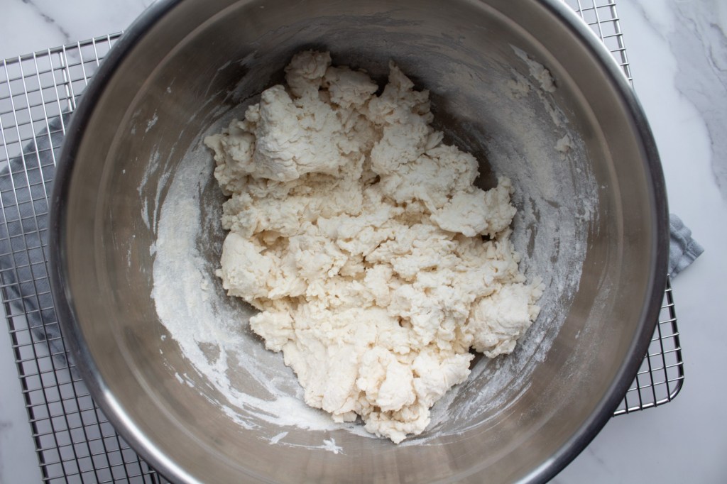 Dough begins to form in a bowl for an easy no knead bagel recipe.