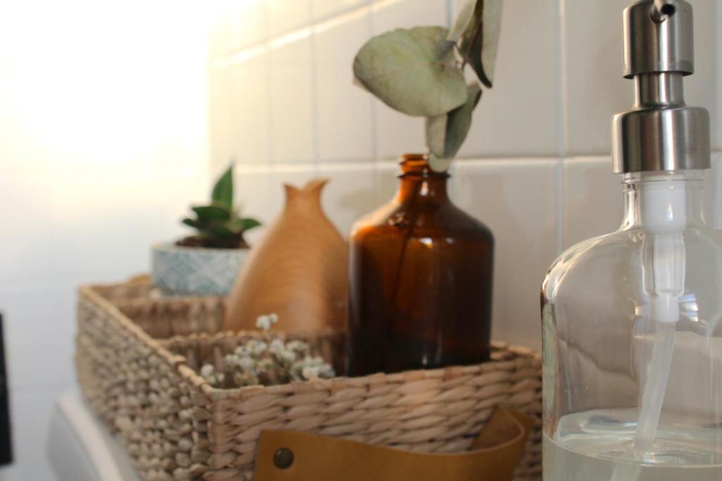 A plant, an essential oil diffuser, a decorative vase, and soap are all on display for this bathroom cleaning checklist.