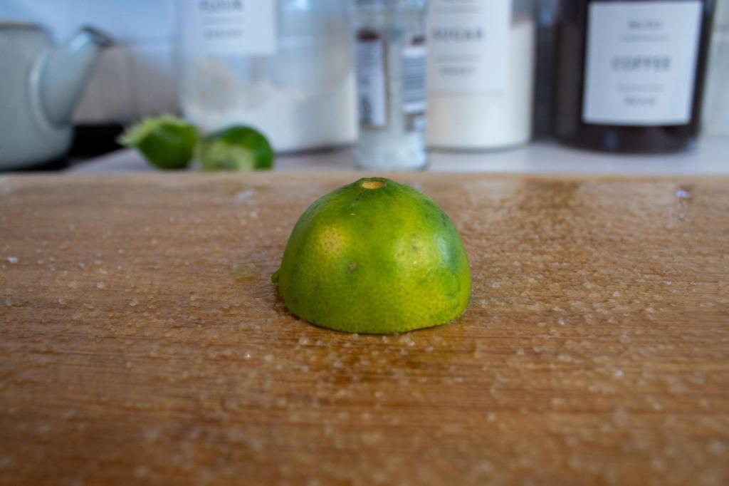 A lime and salt are scrubbed into a wooden cutting board to deodorize it.