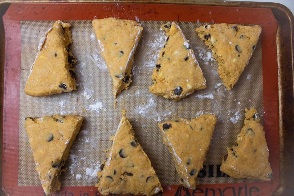 Scones are lined up on a baking sheet before baking.