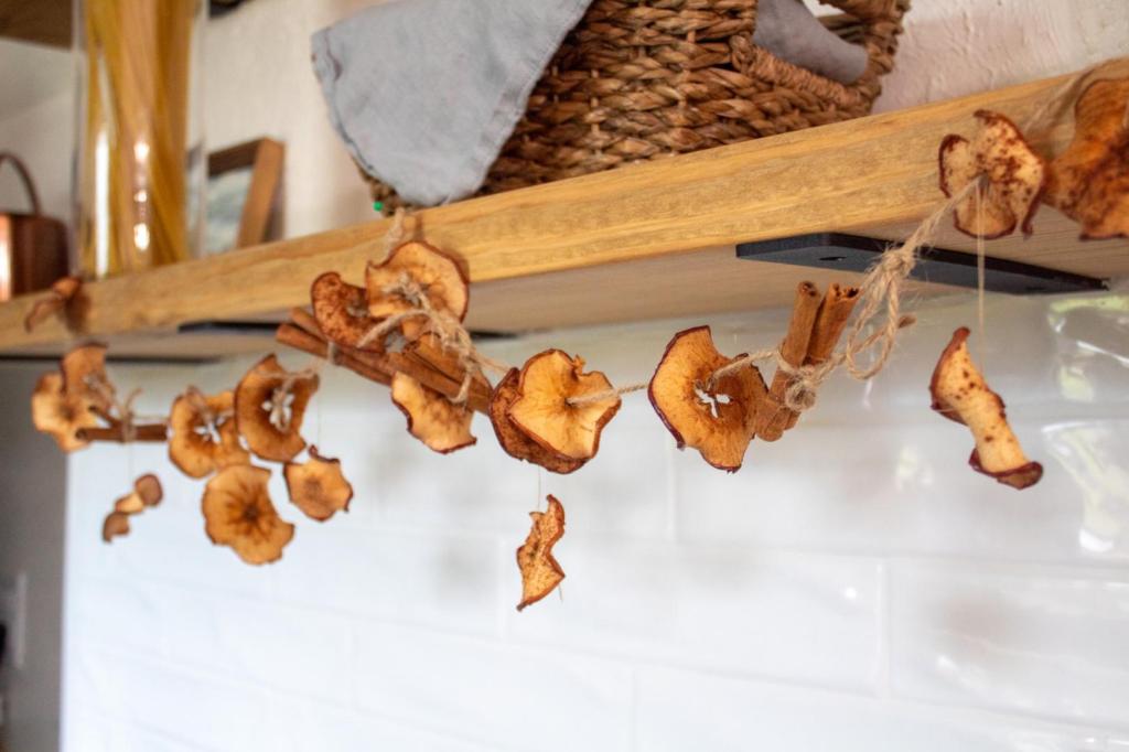 A rustic dried apple garland is hung in a kitchen on floating shelves.