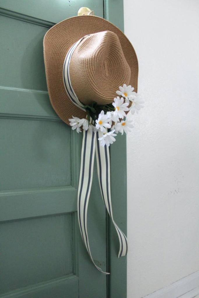 A sun hat wreath is hung on a door knob in a kitchen.