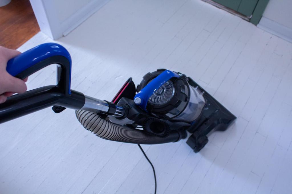 A woman vacuums a hardwood floor to prep for painting.