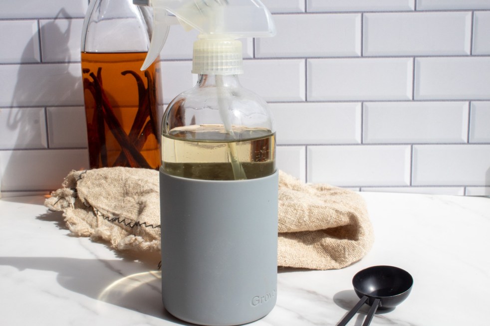 A DIY natural mosquito repellent sits in front of a bottle of vanilla extract.
