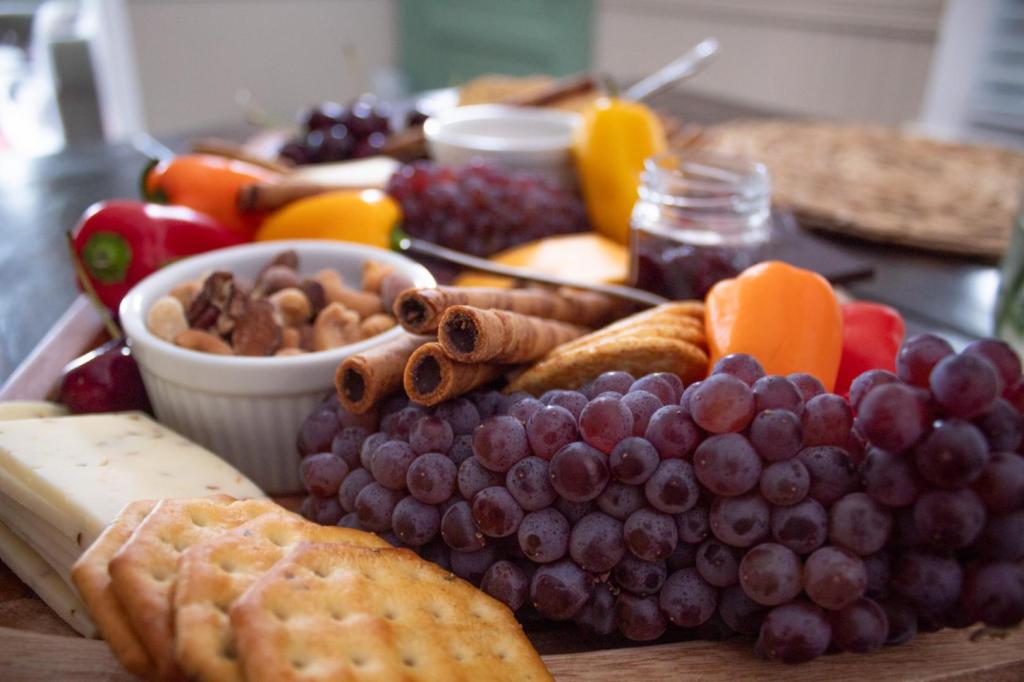Learn how to build a charcuterie board is shown with a board of cracks, cheeses, fruits, and more laid out on a tabletop.