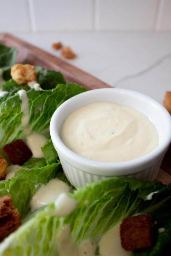 A salad has a homemade greek yogurt dressing made for it on the side.