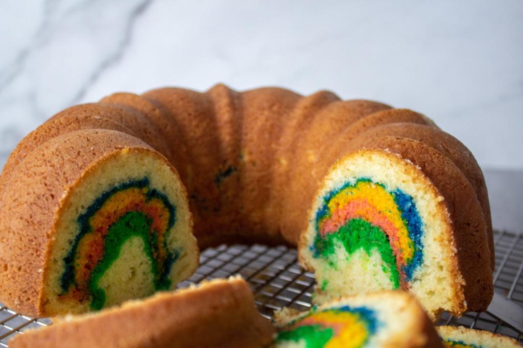 Rainbow colors shine through in a sliced rainbow bundt cake.