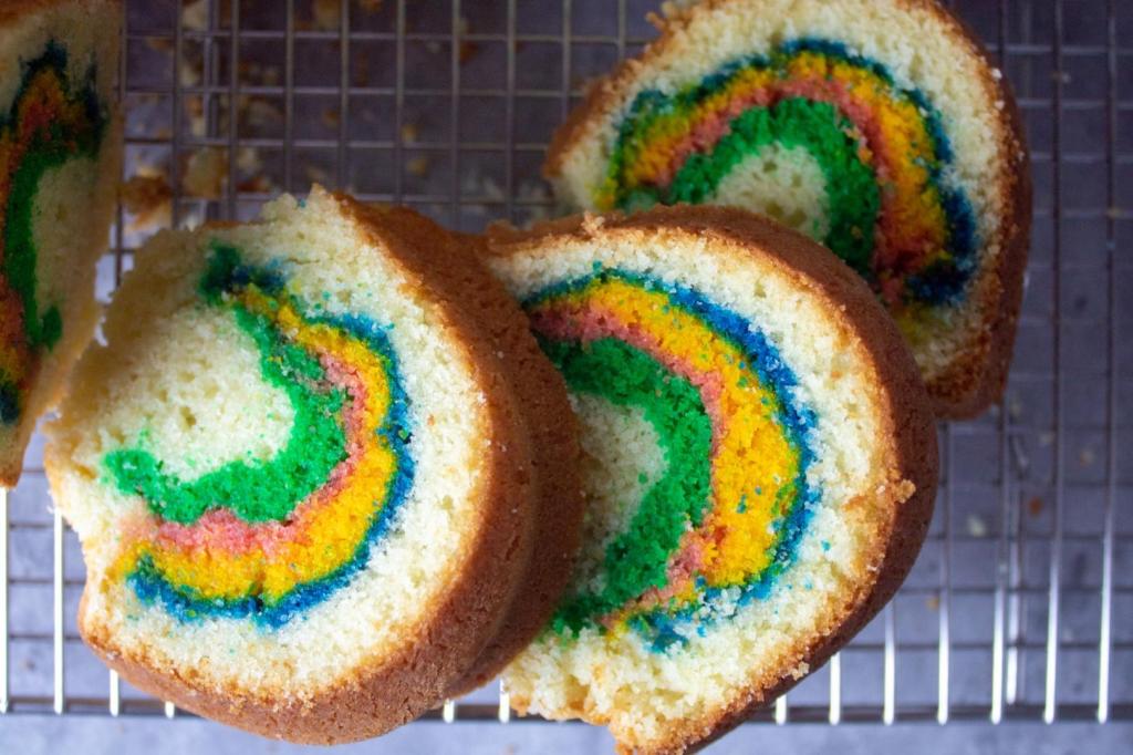 Rainbow colors shine through in a sliced rainbow bundt cake.