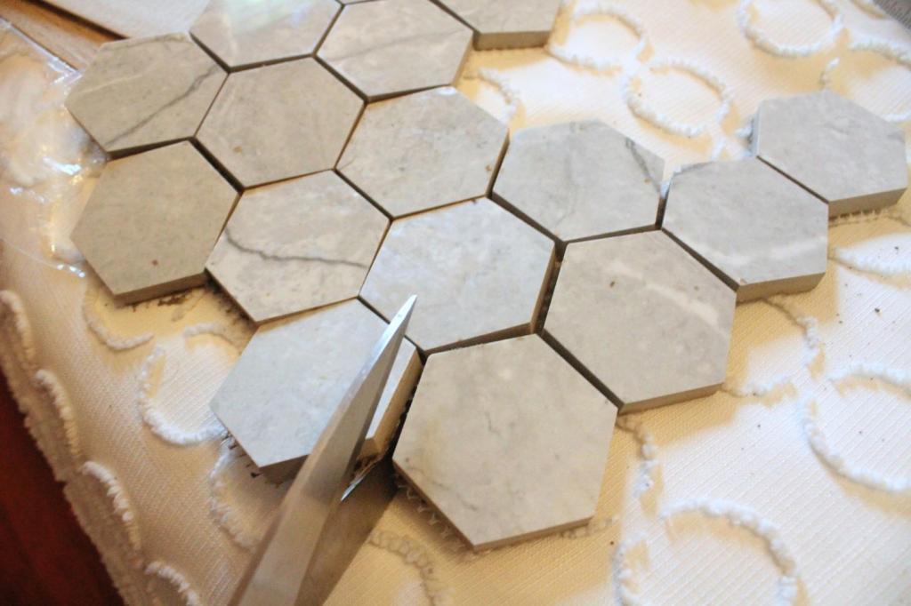 Tile sheets are being cut with scissors for a diy dresser makeover.